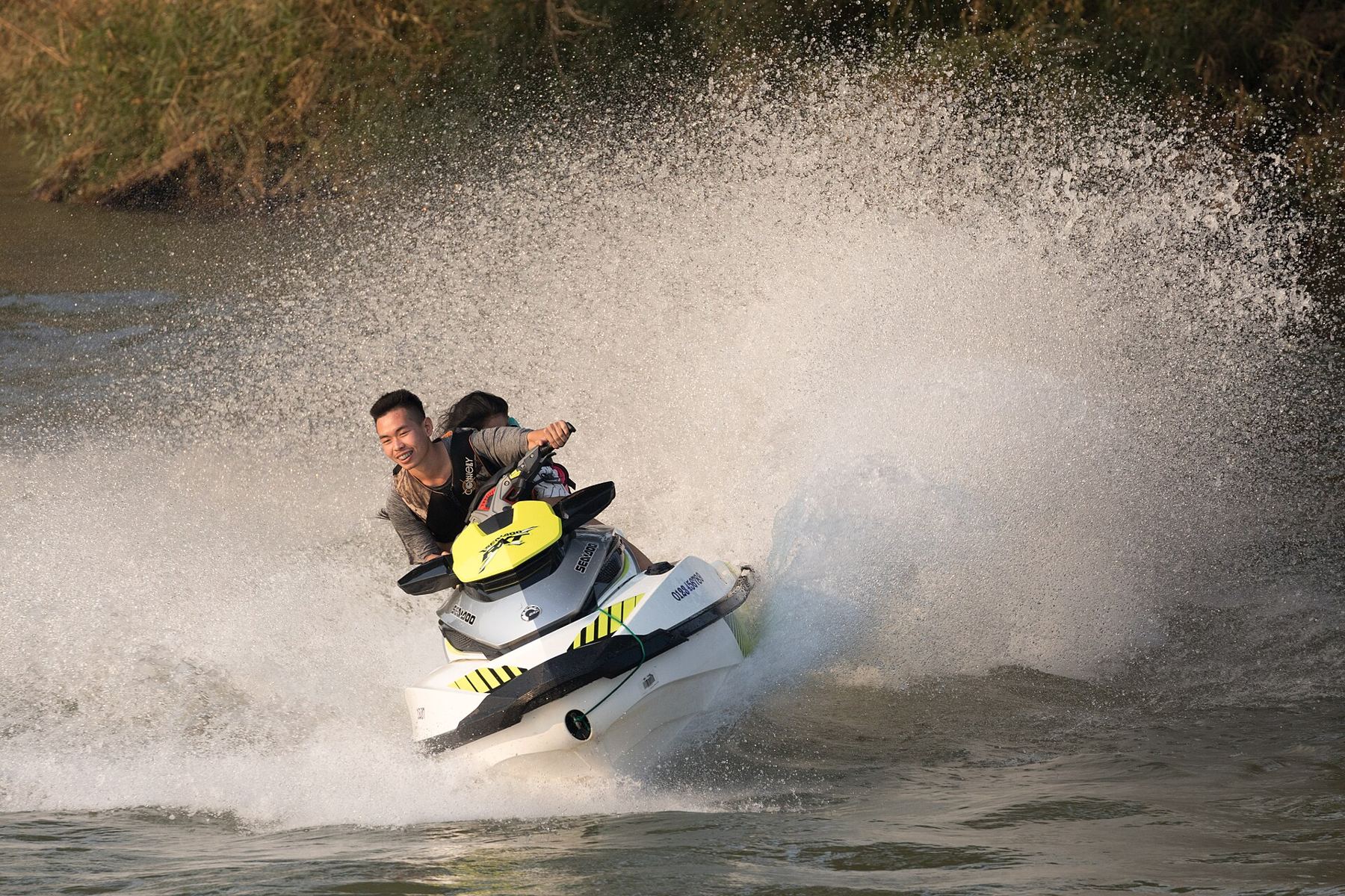 Dos personas en una moto de agua levantando una cortina de agua en un giro